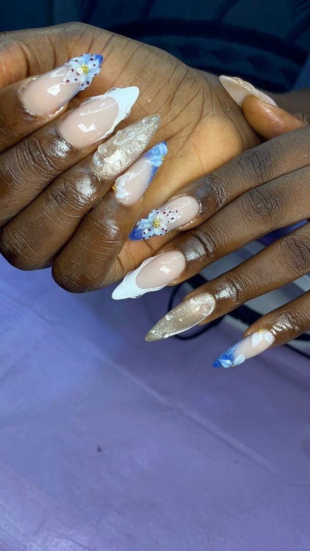 Long stiletto nails with white French tips, gold shimmer and blue 3D flowers