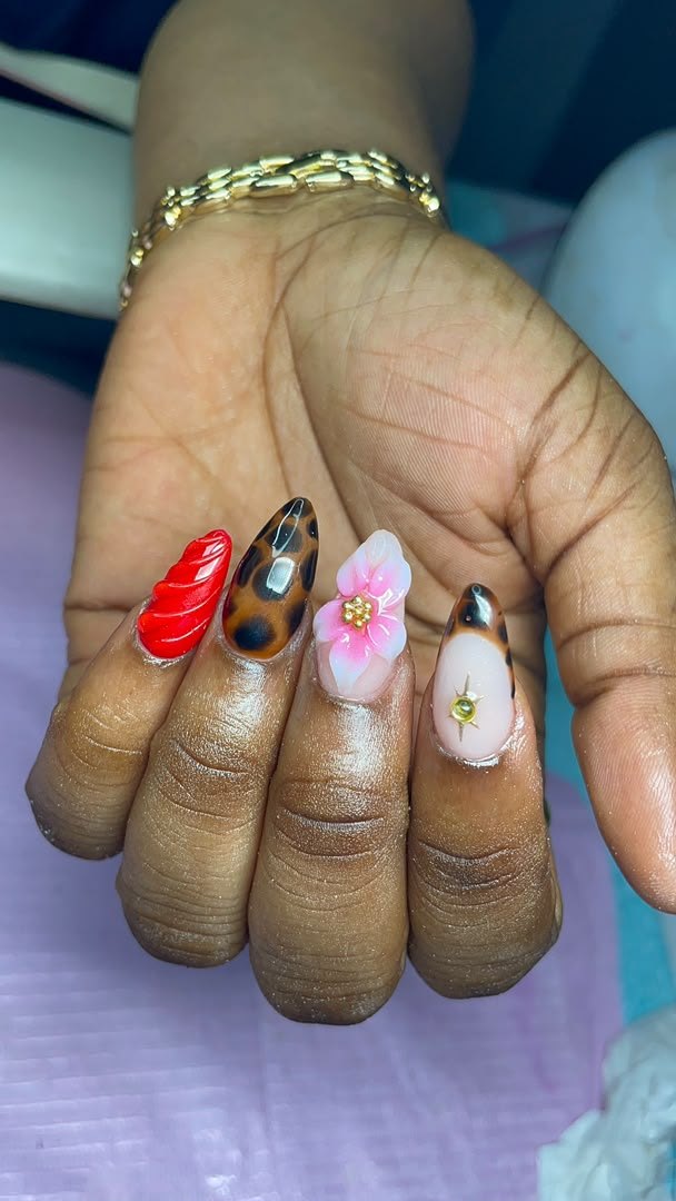 Short almond nails mixing red 3D swirls, tortoiseshell, a pink 3D flower and a gold charm